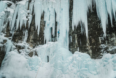 Male ice-climber scaling a massive and treacherous ice wall. 