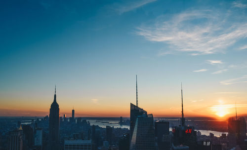 Cityscape against cloudy sky at sunset