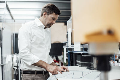 Mature businessman with business plan working while standing in industry