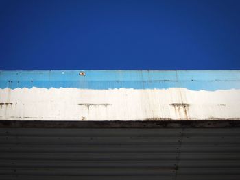 Low angle view of old garage against clear blue sky