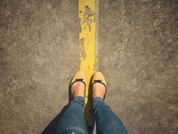 Low section of woman standing over line on road