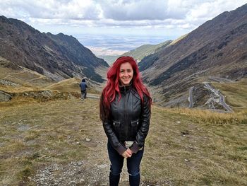 Portrait of young woman standing on mountain against sky