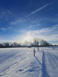 Snow covered field against sky during winter