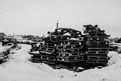 Stacked wooden palettes on snowcapped field during winter