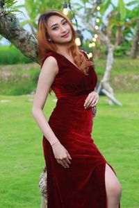 Portrait of young woman standing against tree