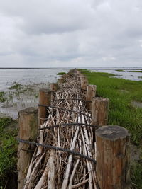 Wooden fence by sea against sky