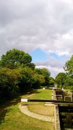 Trees on landscape against cloudy sky