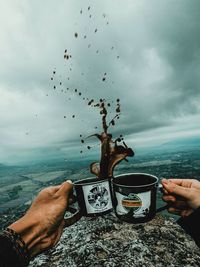 Person holding umbrella by sea against sky