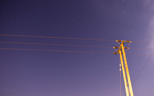 Low angle view of telephone pole against star field at dusk