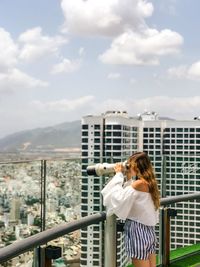 Woman photographing cityscape against sky