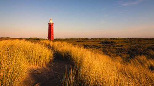 Lighthouse on field against sky