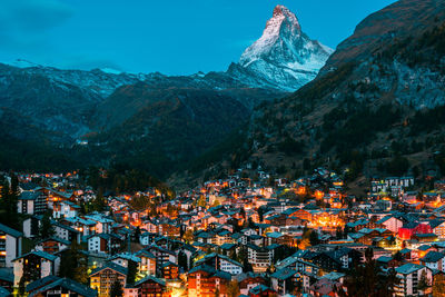 Illuminated buildings in city against sky during winter