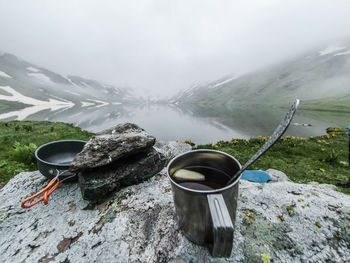 Coffee cup on rock against sky