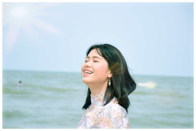 Smiling woman with eyes closed against seascape and sky