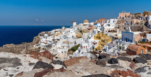 Houses by sea against blue sky