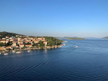 Townscape by sea against clear blue sky