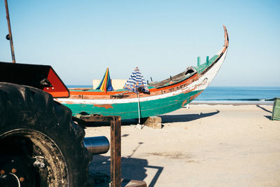 Boats moored on beach against clear sky