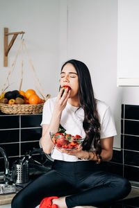 Woman eating strawberry at home