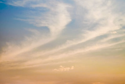 Low angle view of sunlight streaming through clouds during sunset