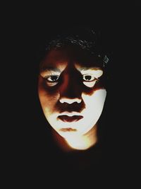 Close-up portrait of young man against black background