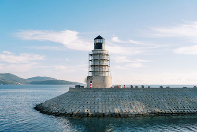 Lighthouse by sea against sky