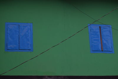 Low angle view of electric lamp against blue wall