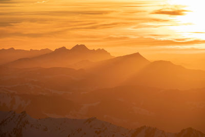 Scenic view of silhouette mountains against orange sky