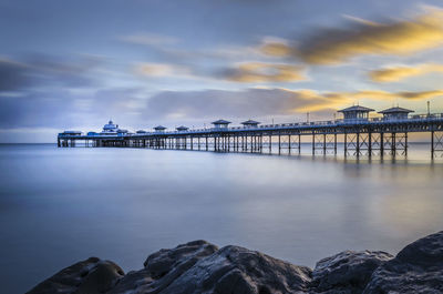 Pier over sea against sky during sunset