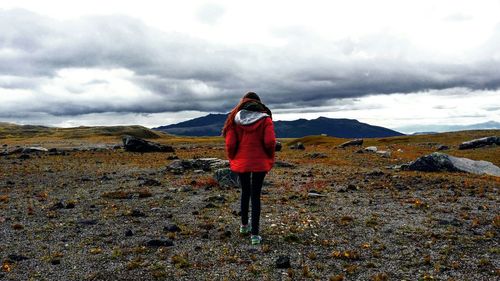 Rear view of woman standing on landscape against sky