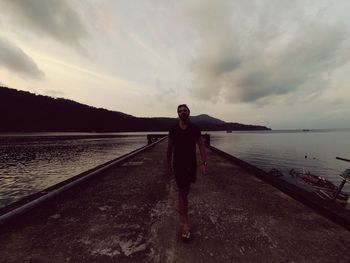 Full length portrait of man standing on sea against sky