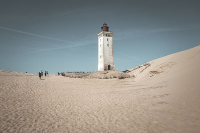 Lighthouse on beach against clear sky