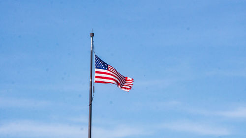 Low angle view of flag against blue sky