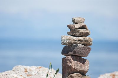 Stack of pebbles by sea against sky