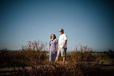 Baby boomer couple smiling and walking along sand dunes