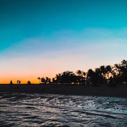 Silhouette trees by sea against sky during sunset