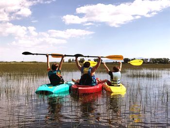 Rear view of siblings kayaking on lake