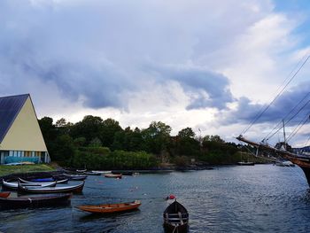 Sailboats moored in river against sky