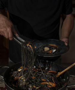 Man is serving black spaghetti.