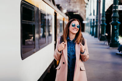 Woman walking by train on railroad station platform