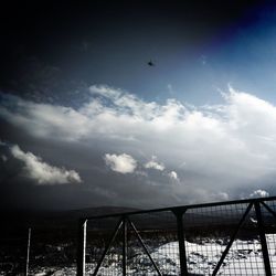 Suspension bridge against cloudy sky