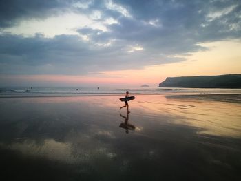 Silhouette person on beach against sky during sunset