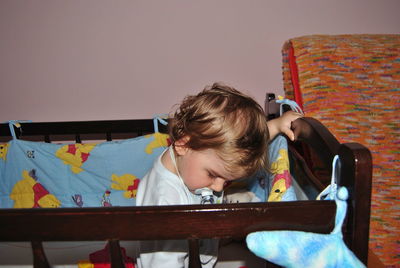 Cute baby boy sucking pacifier in crib at home