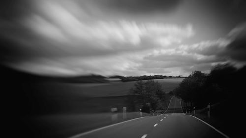 Road by trees against sky