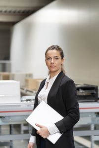 Confident businesswoman with tablet pc standing in factory