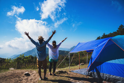 Rear view of friends standing on land against sky