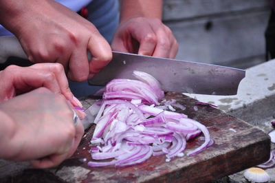 Cropped image of man and woman chopping onions in kitchen