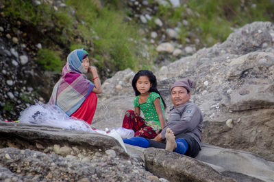 Full length of friends sitting on rock