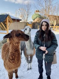 Portrait of young woman with horse standing in winter