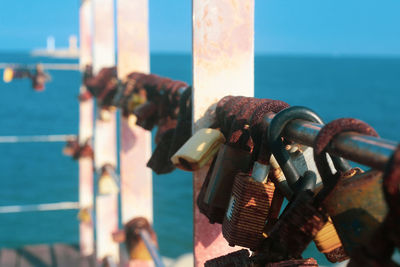 Close-up of padlocks on railing against sea