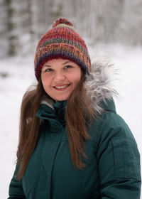 Portrait of young woman standing against trees during winter